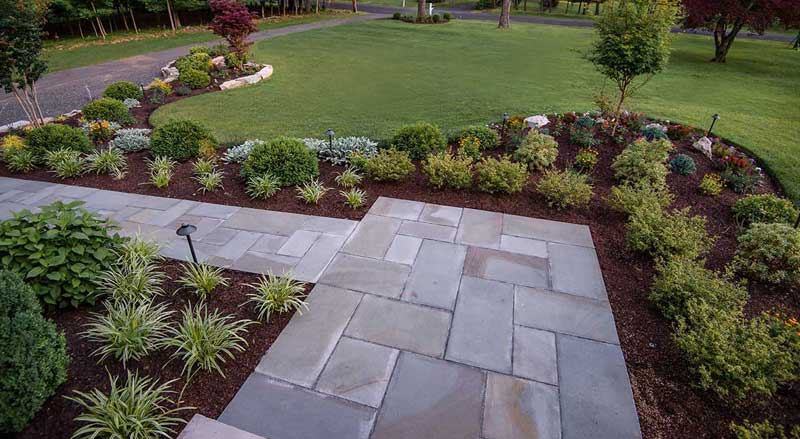 Elegant front yard landscape design with staggered plant heights, layered textures, and curved garden