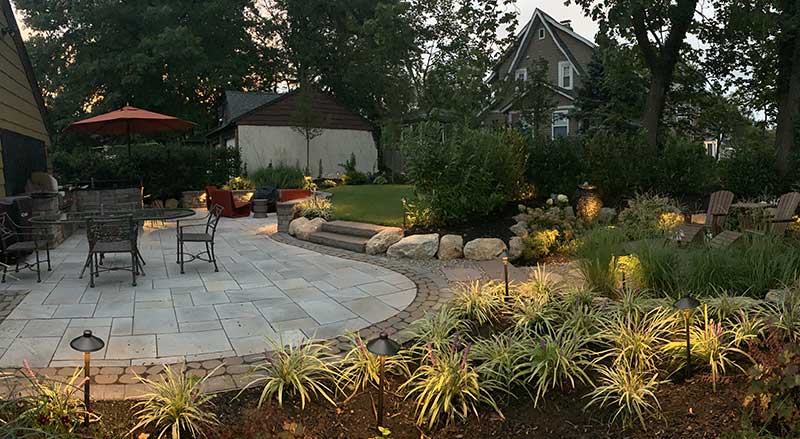 An outdoor space with a seating area, stone path, and water feature