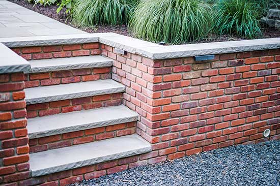 Red brick landscape masonry steps and retaining wall with chiseled edge caps