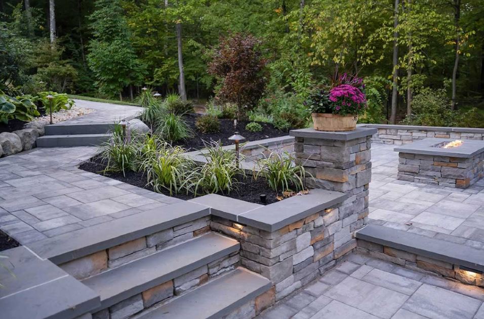 Multi-level backyard landscape featuring custom paver patio, retaining walls, stone steps, and integrated landscape design built for long-term enjoyment