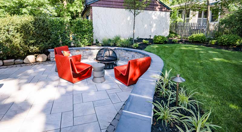 Curved patio with retaining wall that also serves as a seat wall for a firepit