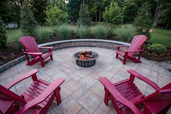 Custom curved paver patio design with sitting wall and firepit.