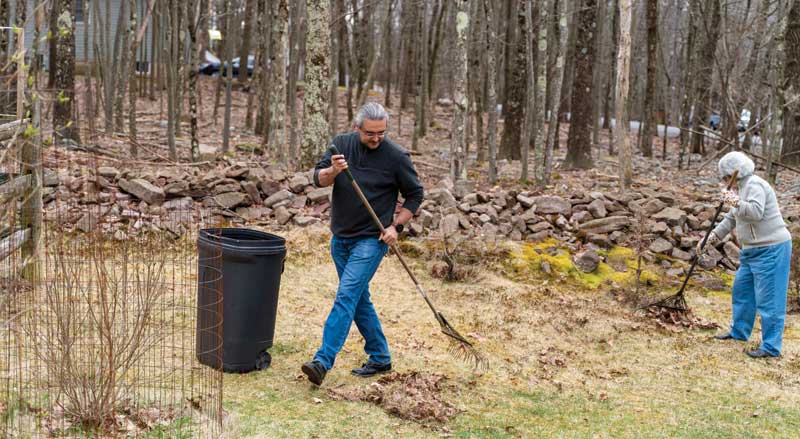 older man and woman raking leaves in yard