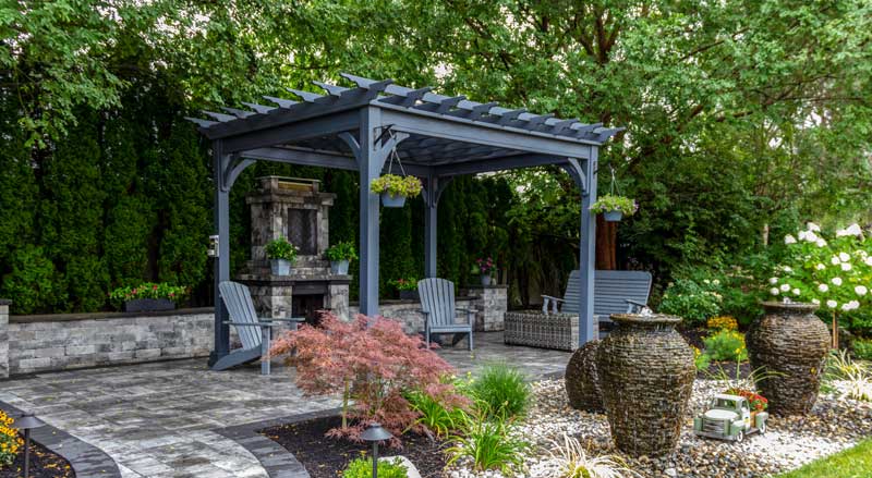 a bluestone custom patio with a blue pergola in a lush, green backyard.
