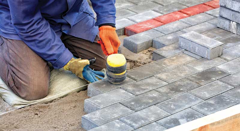 A man hammering pavers together for hardscape design