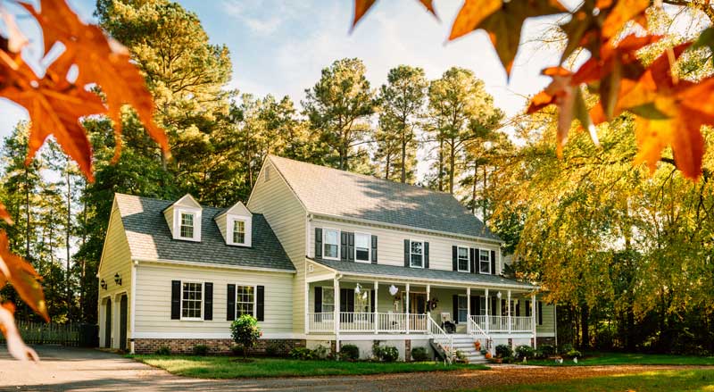 New Jersey home framed by colorful fall foliage, highlighting the importance of seasonal yard prep before winter.