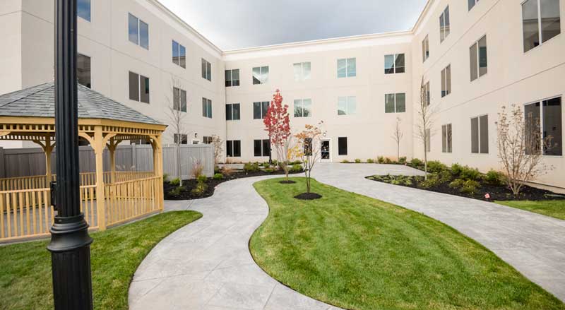 Well-maintained HOA courtyard featuring curved walkways, green lawn, new plantings, and a gazebo