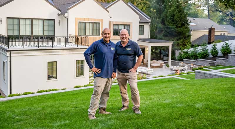 Landscape Solutions team standing on a maintained lawn in front of a luxury residential property