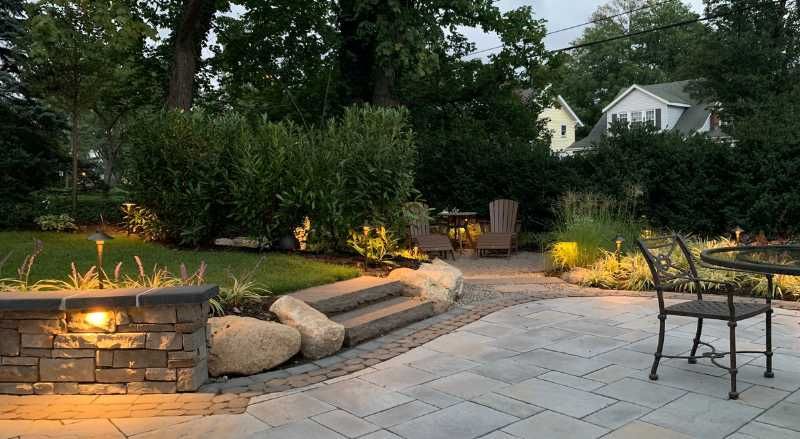 Stone patio with cozy seating area illuminated by outdoor lighting