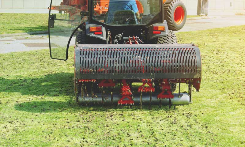 Commercial lawn aerator removing soil plugs on lawn