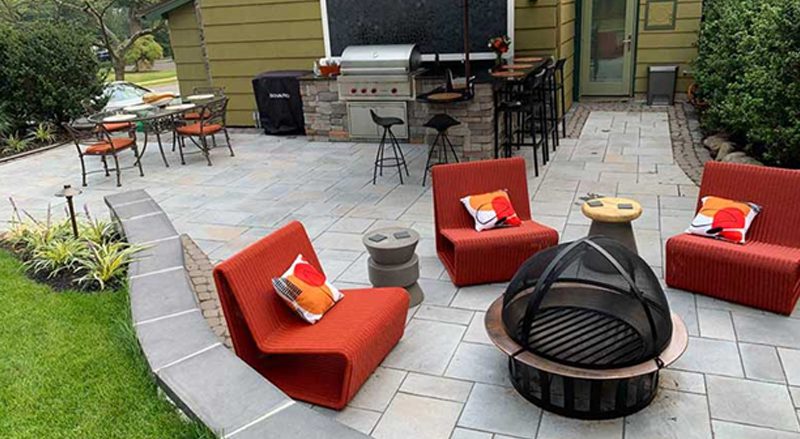 An outdoor patio with grill, bar, firepit and dining areas