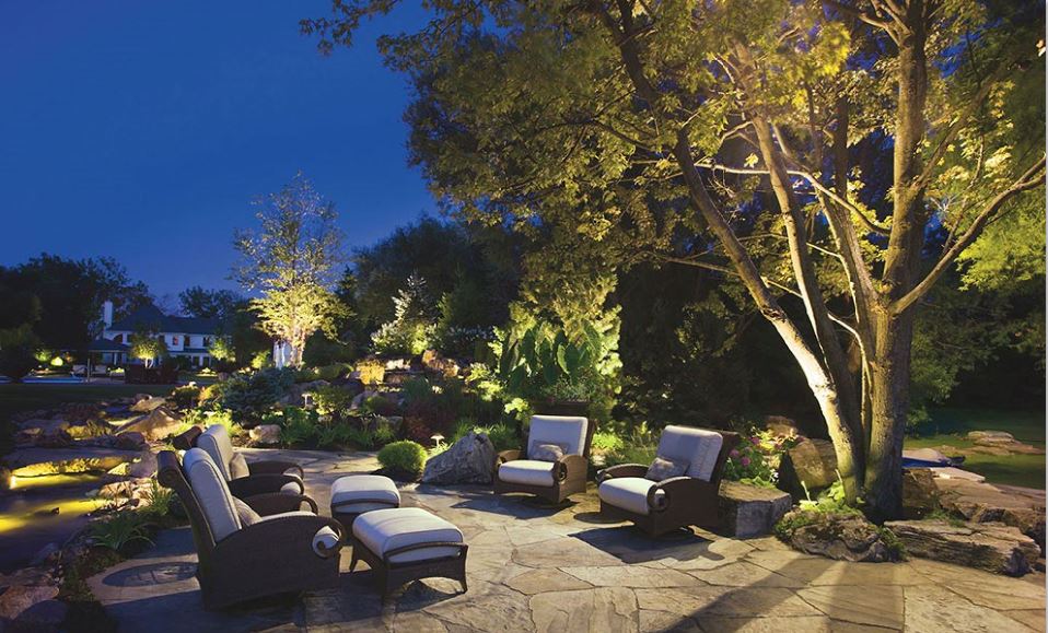 Professionally designed outdoor living space with stone patio, retaining walls, planting beds, and fire feature in a New Jersey backyard