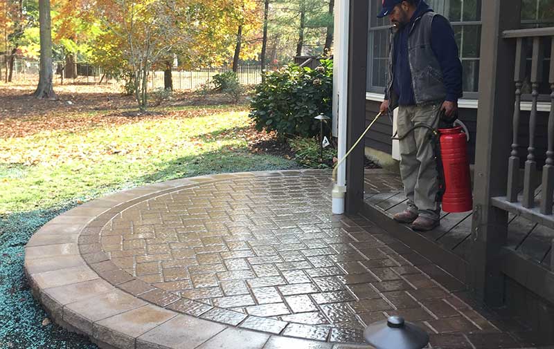 Landscaper sealing a curved paver patio