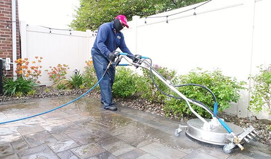 Landscaper using a professional power washing machine on a paver patio