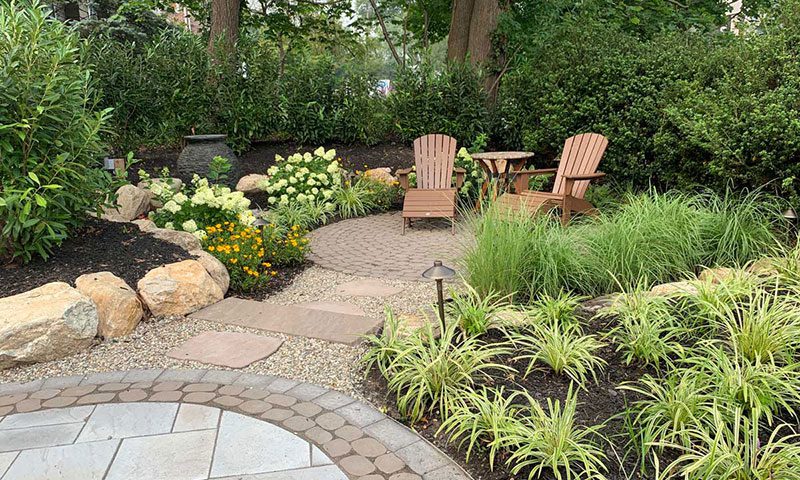 Two Adirondack chairs and a table on a secluded garden patio