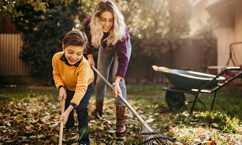 Mother and son raking leaves in yard