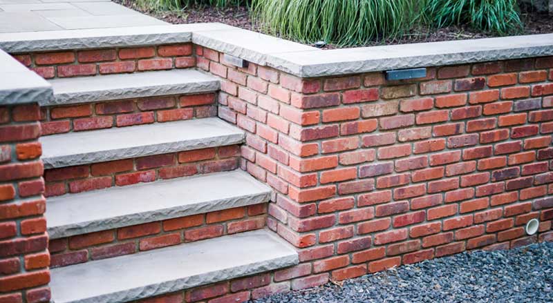 Brick retaining wall with stone steps illustrating structural hardscaping that may require permits