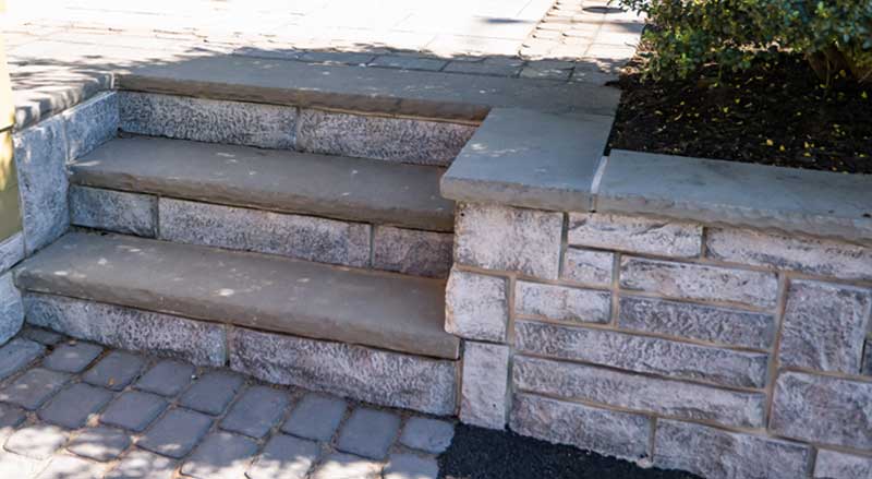 Stone retaining wall with steps going up to a raised patio
