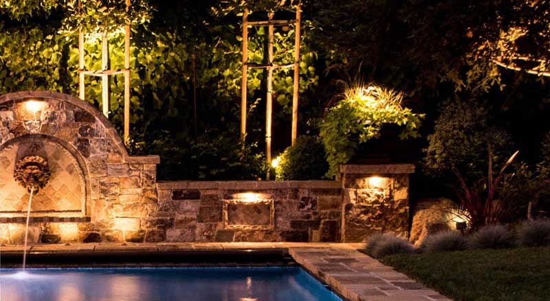 Nighttime view of a pool and a fountain with glowing lights