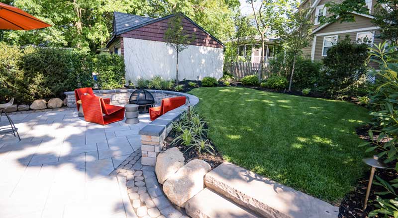 Backyard patio with fire pit seating, fresh lawn, and newly maintained landscape beds for spring
