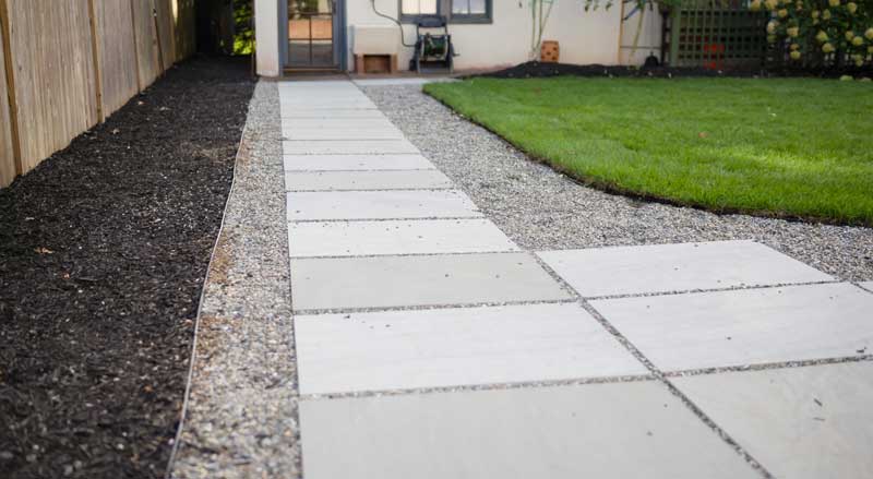 Bluestone paver walkway with gravel edging and manicured lawn at a New Jersey home.