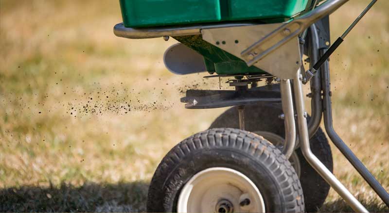 Spreader overseeding grass to strengthen lawns before the New Jersey fall and winter seasons