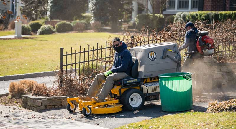 Landscape Solutions team performing seasonal cleanup with mowing and leaf blowing services in preparation for fall and winter