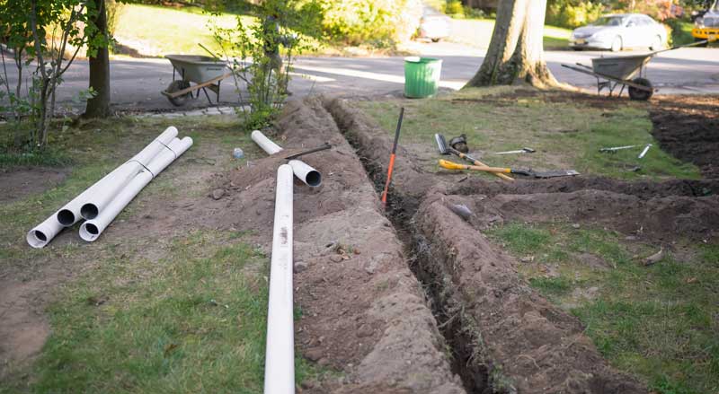 Drainage pipes are being installed in a homeowner’s front yard