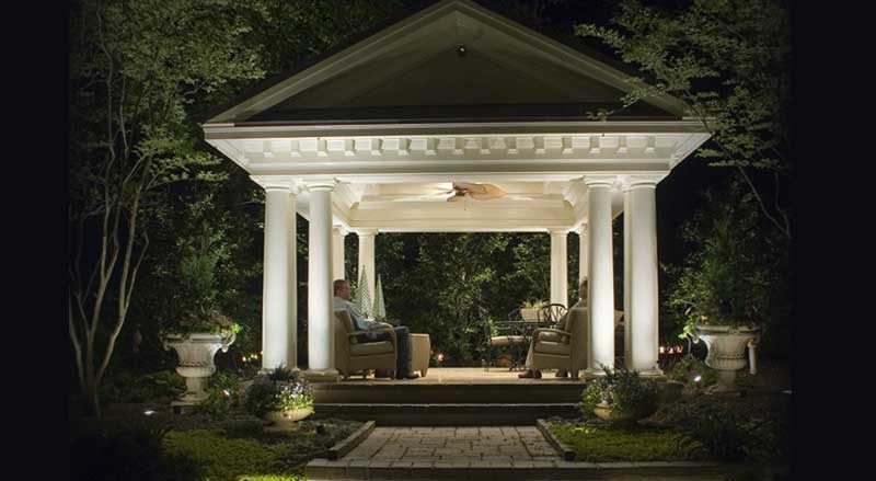 Elegant, columned garden pavilion with lighting and outdoor furniture