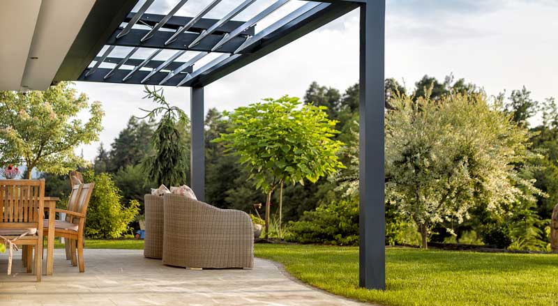 Modern backyard patio with pergola and outdoor seating surrounded by lush landscaping, ideal for early hardscape planning