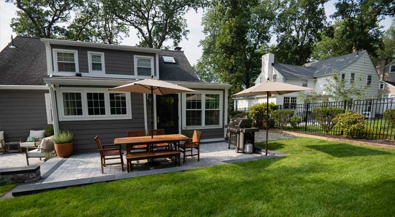 Residential backyard patio and outdoor dining space with clean lawn and spring landscape maintenance