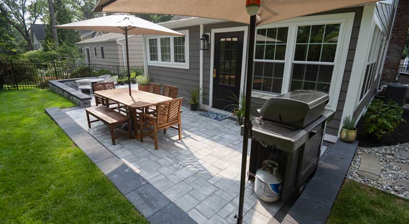 Custom backyard patio with dining area, grill station, and outdoor lounge area