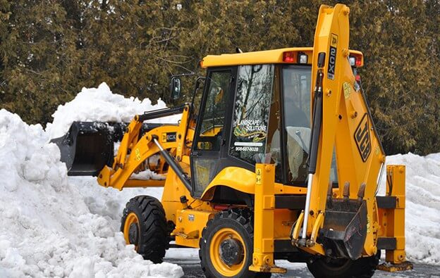 Landscape Solutions uses heavy equipment while removing snow from a parking lot for a large commercially owned property