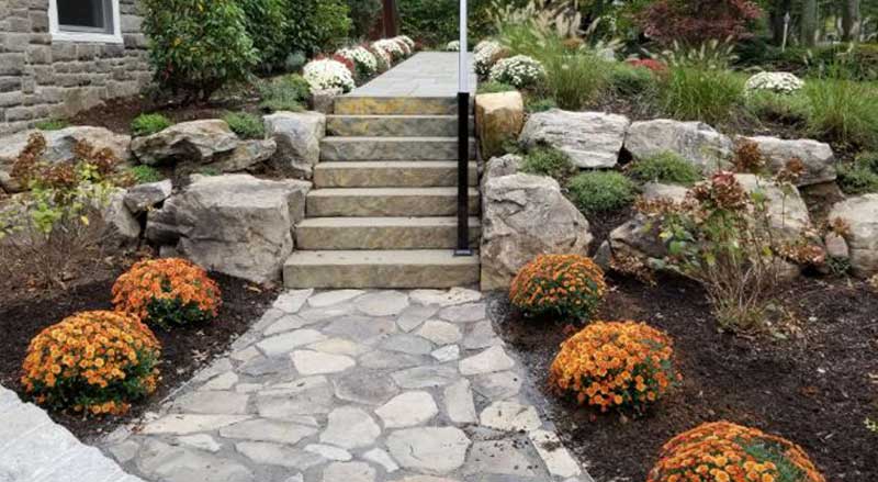 Natural stone steps with boulder retaining walls and seasonal plantings for a New Jersey landscape
