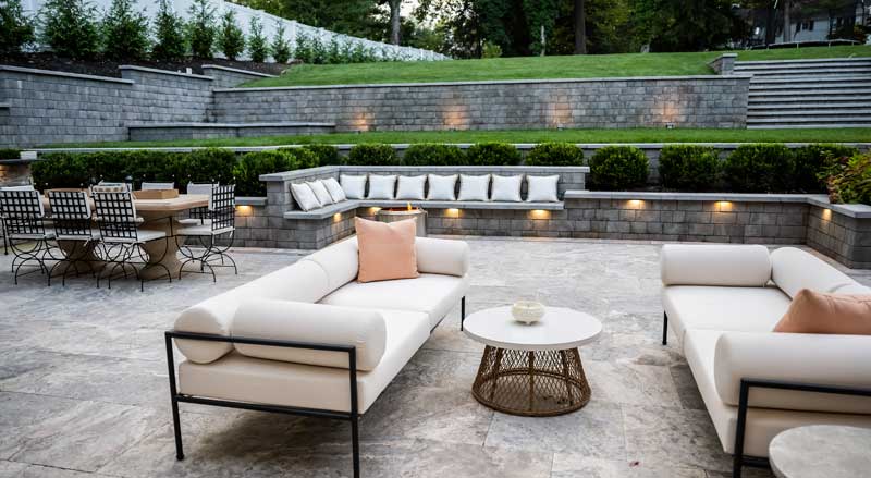 Spacious tiered patio with built-in stone seating and ambient lighting.